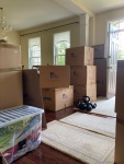 Several moving boxes are piled up beside the front door to a house, ready to be moved out.